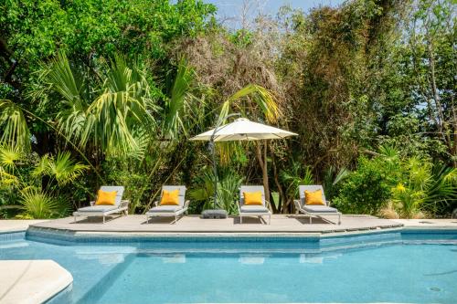 um grupo de cadeiras e um guarda-sol junto a uma piscina em Casa Manglar Riviera Maya em Puerto Aventuras