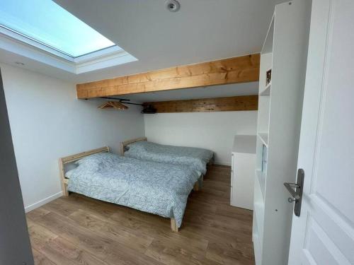 - une chambre avec 2 lits dans une chambre dotée d'une lucarne dans l'établissement Bundle 2 Duplex Argenté 20 min Paris Saint Lazare, à Argenteuil