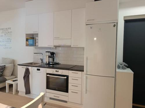 a kitchen with white cabinets and a white refrigerator at Uusi kaksio parvekkeella ja autopaikalla in Joensuu