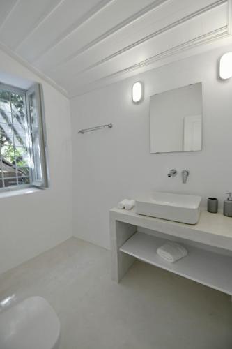a white bathroom with a sink and a mirror at Abri Hydra in Hydra