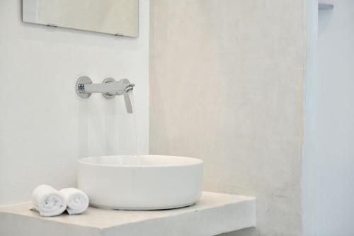 a white bathroom with a sink and towels on a counter at Abri Hydra in Hydra