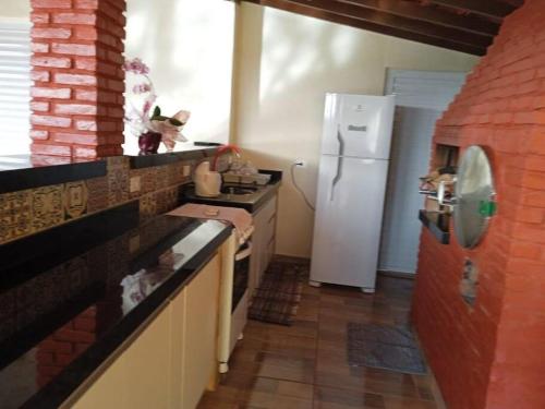 een keuken met een witte koelkast en een rode bakstenen muur bij Casa com piscina in Andirá