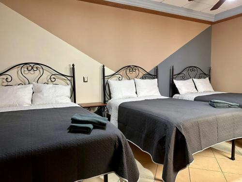 a bedroom with two beds with black blankets at Hotel Hacienda el Edén in San Juan de los Lagos