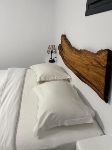 a bed with white pillows and a wooden headboard at The Coast Suites in Tourlos