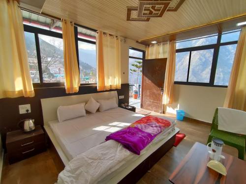 a bedroom with a bed and a table and windows at Singhdwar Homestay in Joshīmath