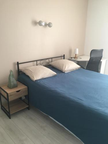 een slaapkamer met een blauw bed en een stoel bij Maison avec jacuzzi in Saintes