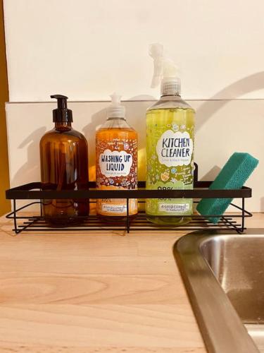 trois bouteilles de liquide posées sur une étagère dans une cuisine dans l'établissement Jolie maison avec jardin au calme en ville, à Limoges