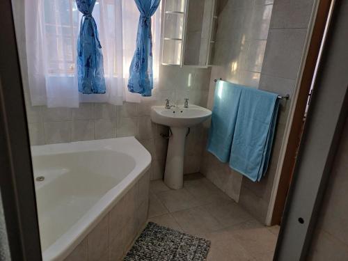 a bathroom with a sink and a bath tub and a sink at Serene on 5 Cologne in Germiston