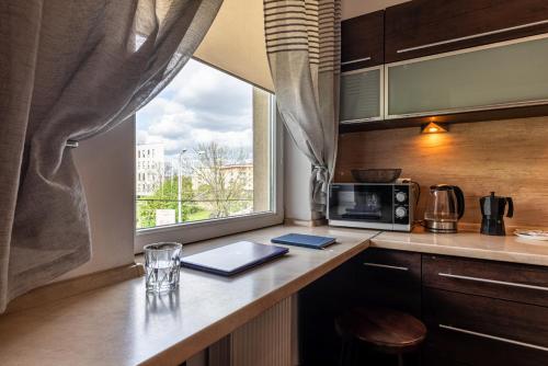eine Küche mit einer Theke mit einer Mikrowelle und einem Fenster in der Unterkunft Wrocław Apartment - Balcony, Park and Tram nearby - by Rentujemy in Breslau