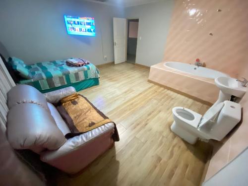 MOMENTS Of JOY GUESTHOUSE AND SPA AT CARNIVAL في Brakpan: حمام به أريكة ومغسلة وحوض استحمام