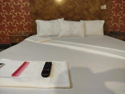 a white bed with a remote control on a towel at Hotel Highway Link in Karachi