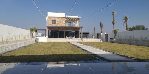 een huis met een gazon voor een gebouw bij الاستراحة الشموخ in Mu‘tamar