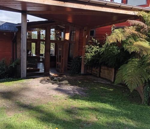 - une terrasse couverte à l'avant d'une maison rouge avec des portes en verre dans l'établissement Lodge El Taique, à Puyehue