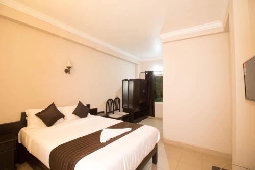 um quarto com uma cama grande e uma televisão em Munnar Mount Shelt Hotel em Munnar