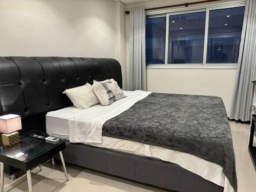 um quarto com uma cama grande e uma cabeceira preta em Apto Lujoso, piscina climatizada, jacuzzi, gym. em Assunção