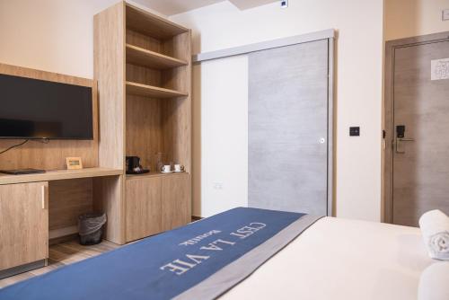 a bedroom with a bed with a tv and a closet at C'est La Vie Boutik Swieqi in Is-Swieqi