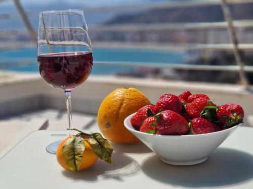 a bowl of fruit and a glass of wine on a table at Casa Buena Vista con piscina y ascensor in Cullera