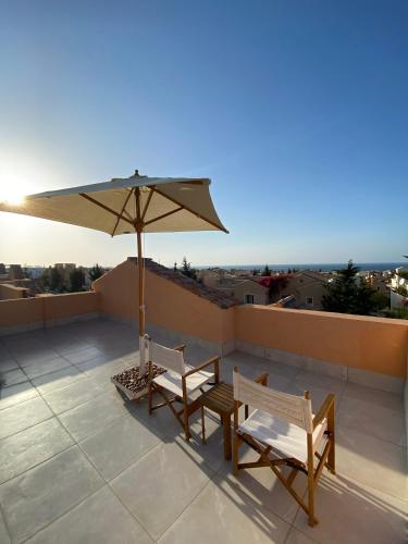 a patio with two chairs and an umbrella on a roof at Luxury Beach Living in Mountain View in Ras Elhekma