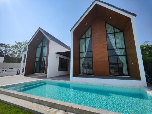 une maison avec une piscine en face de celle-ci dans l'établissement ASTRID PoolVilla KhaoYai, à Pak Chong