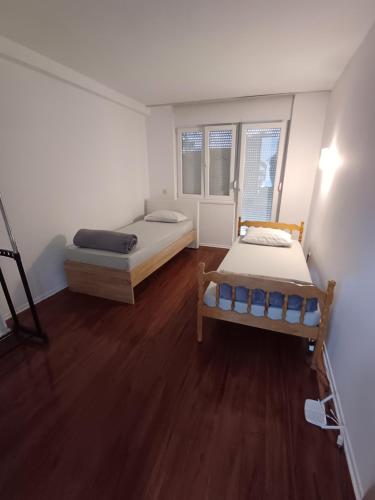 two beds in a room with wooden floors at Čapljina Rooms in Čapljina