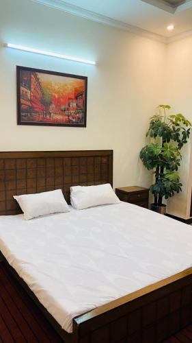 um quarto com uma grande cama branca com um quadro na parede em Gem lodges em Islamabad
