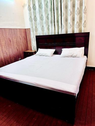 um quarto com uma cama grande e lençóis brancos em Gem lodges em Islamabad