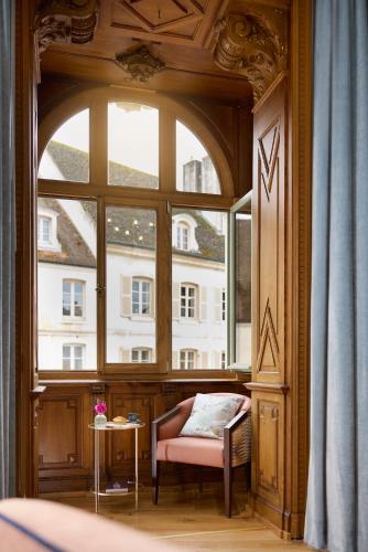 a room with a large window with a chair and a table at Maison 1896 in Beaune