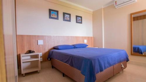 Schlafzimmer mit einem Bett mit blauer Bettwäsche und einem Spiegel in der Unterkunft Piazza Di Roma in Caldas Novas