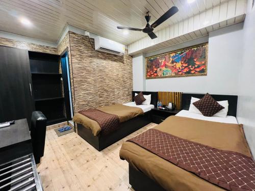 Habitación de hotel con 2 camas y ventilador de techo. en Hotel Sabera, en Siliguri