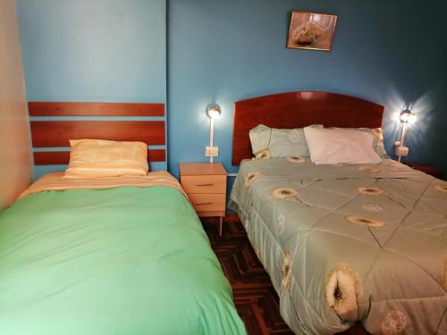 2 camas en un dormitorio con paredes azules en Naty's Guest House, en Cusco