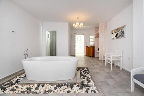 a white bath tub in a bathroom with rocks on the floor at Maistros Village in Karterados