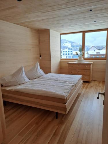 - une chambre avec un grand lit et une grande fenêtre dans l'établissement NEU Uuszit985 - auszeit mit ausblick, à Schwarzenberg im Bregenzerwald