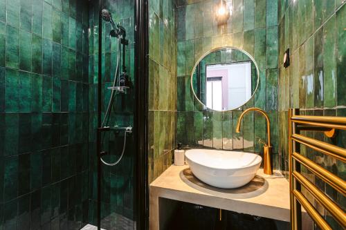 a green tiled bathroom with a sink and a mirror at Le baroque Rochelais in La Rochelle
