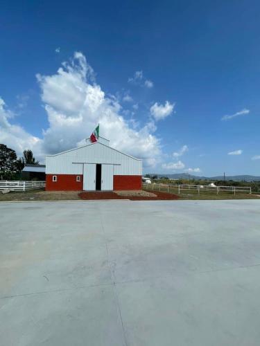 a red and white barn with a large parking lot at Cabaña tipo granero Granglam Ixkapada glamping in Ixtapan de la Sal