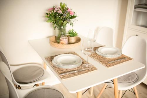 un tavolo bianco con due piatti e un vaso di fiori di Schön gelegene Ferien-/Pendlerwohnung nahe Rothaarsteig mit guter Anbindung a Haiger