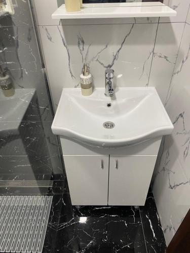 a white sink in a bathroom with black tiles at Apartman Repac in Ostrovo
