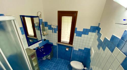 a blue and white bathroom with a toilet and a sink at ENJOY HOUSE in Ronchi