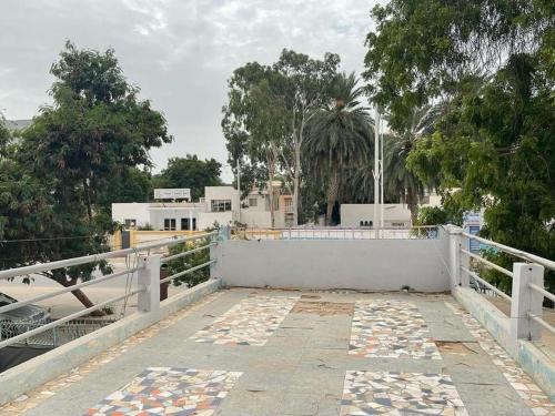 a white fence and a walkway with trees and buildings at Auberge-Cafe Tunisie in Nouakchott