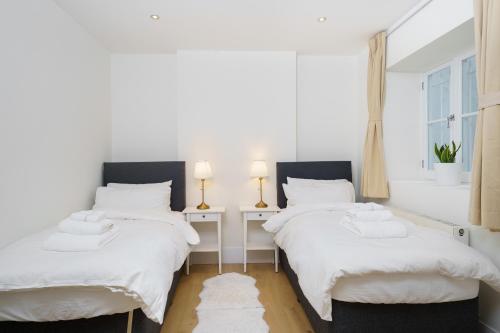 two twin beds in a room with a window at 2 bedroom flat in Pimlico & Westminster in London
