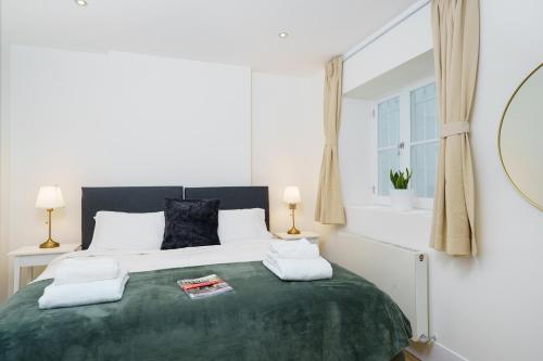 a bedroom with a large green bed with two lamps at 2 bedroom flat in Pimlico & Westminster in London