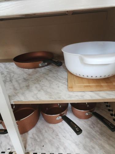 a kitchen shelf with a bowl and pans on it at Cozy bungalow in Calgary
