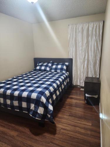 una camera con un letto con una coperta a scacchi blu e bianca di Cozy bungalow a Calgary