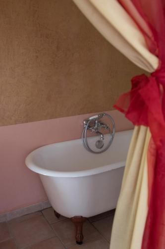 La salle de bains est pourvue d'une baignoire et d'un rideau rouge. dans l'établissement Le Mas de Ponge, à Nîmes