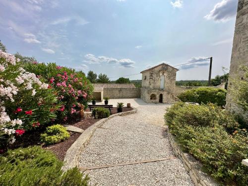 un giardino fiorito e un edificio in pietra di Le Mas de Ponge a Nîmes