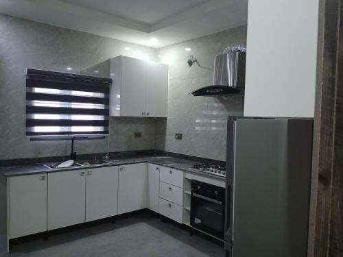 a kitchen with white cabinets and a stainless steel refrigerator at Dixonlux apartment in Galadima