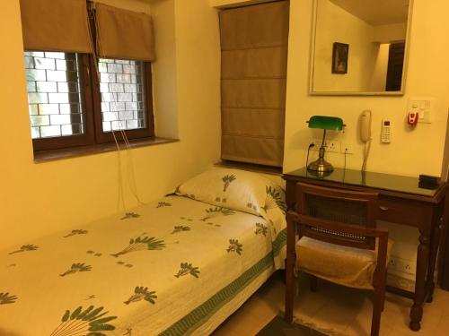 a bedroom with a bed and a desk and a table and chair at Lutyens Bungalow in New Delhi