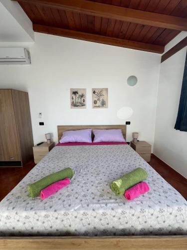 a bedroom with a large bed with pink and green pillows at Villa Alelida in Cinisi