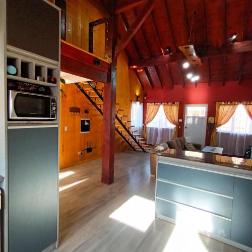 uma cozinha e sala de estar com paredes vermelhas e pisos em madeira em El sueño del flaco em San Martín de los Andes