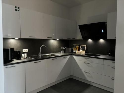 a kitchen with white cabinets and a sink at KeyHosting Apartment Zentral Parkplatz in Aschaffenburg