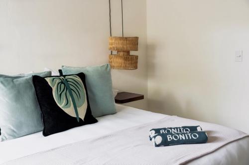 a bed with a pillow with a book on it at Residencia Tropical Don Bonito in Sayulita